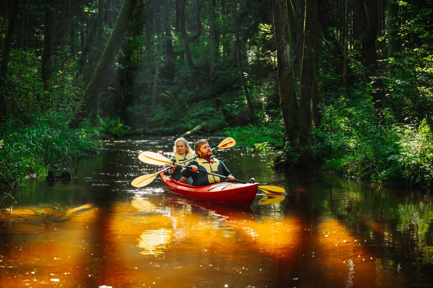 Zwei Personen beim Kajakfahren auf einem Waldfluss in Dzūkija nahe Druskininkai